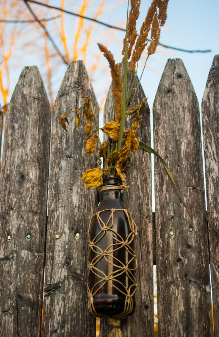 Use empty wine bottles to hang flower vases on your fence. You can choose different kinds of bottles and flowers, whatever you like is great! Here are some quick and easy ways to decorate your garden fence.  